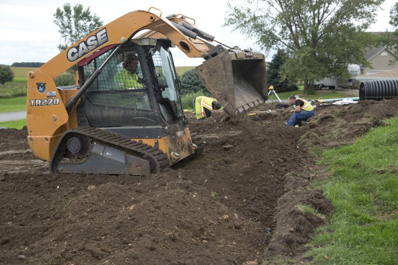 Colby Nichols of North Iowa Septic Solutions operates a Case TR270 skid loader with a Stout Skeleton Rock Bucket while covering chambers in a drainfield for a septic installation. (Photo by Mark Hirsch)